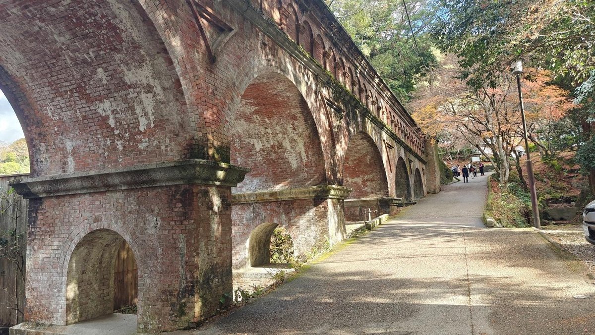Historic red brick aqueduct beside tree-lined pathway