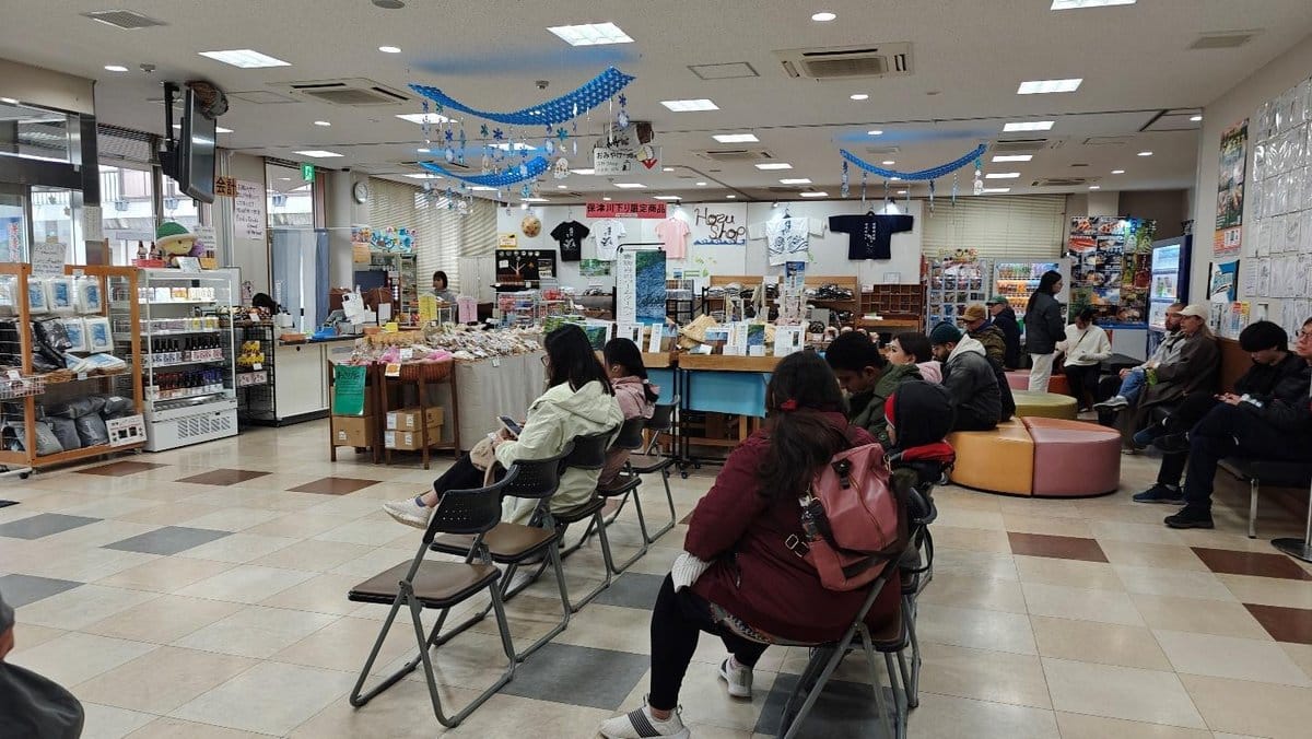 Indoor market seating area with people and merchandise.