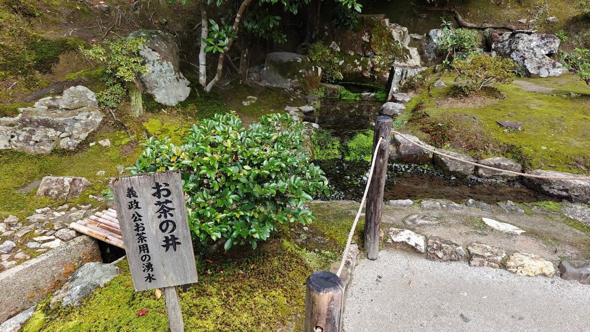 Japanese garden with stone path and sign, lush greenery
