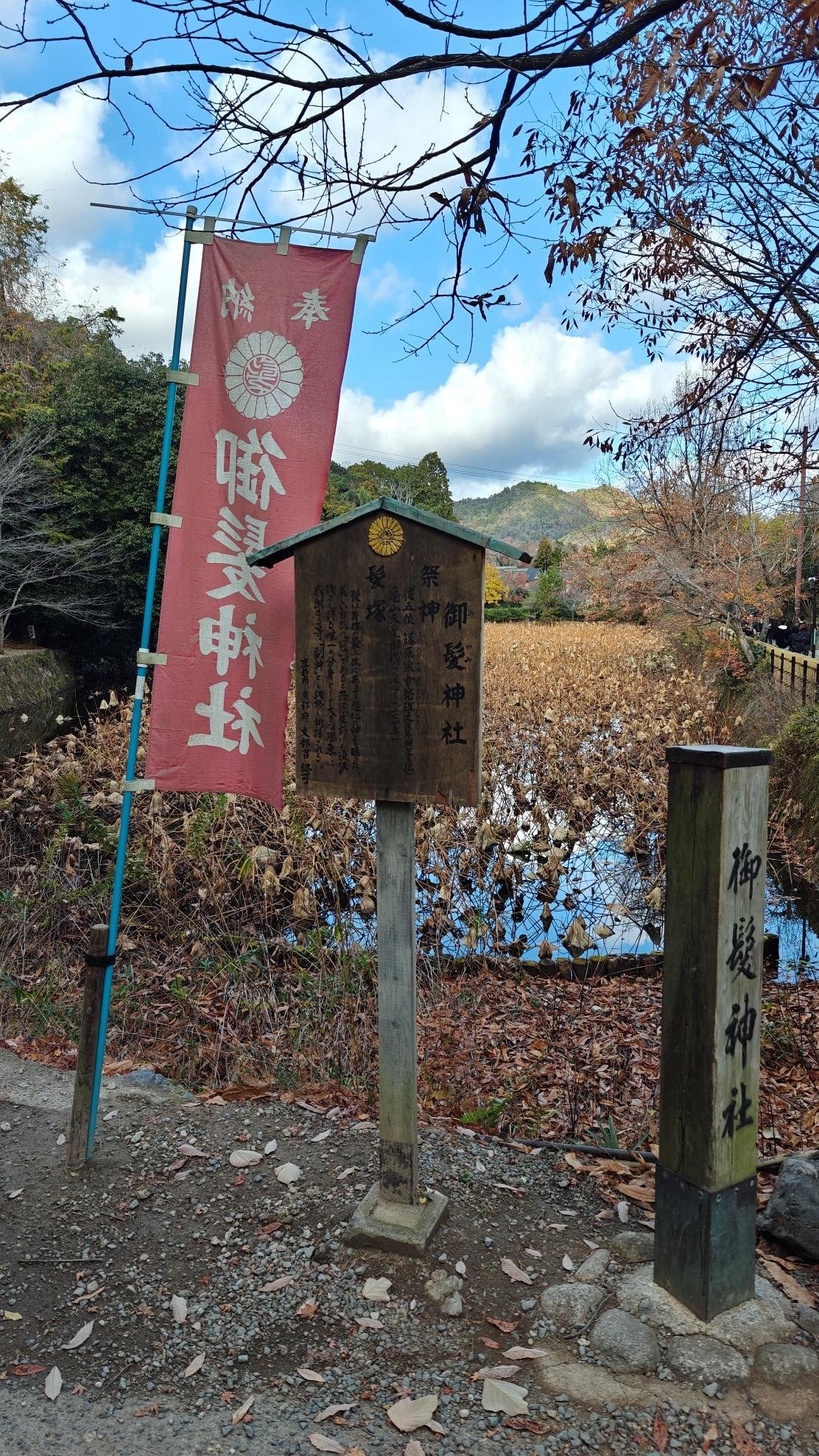 Japanese shrine signs near autumnal pond and mountains