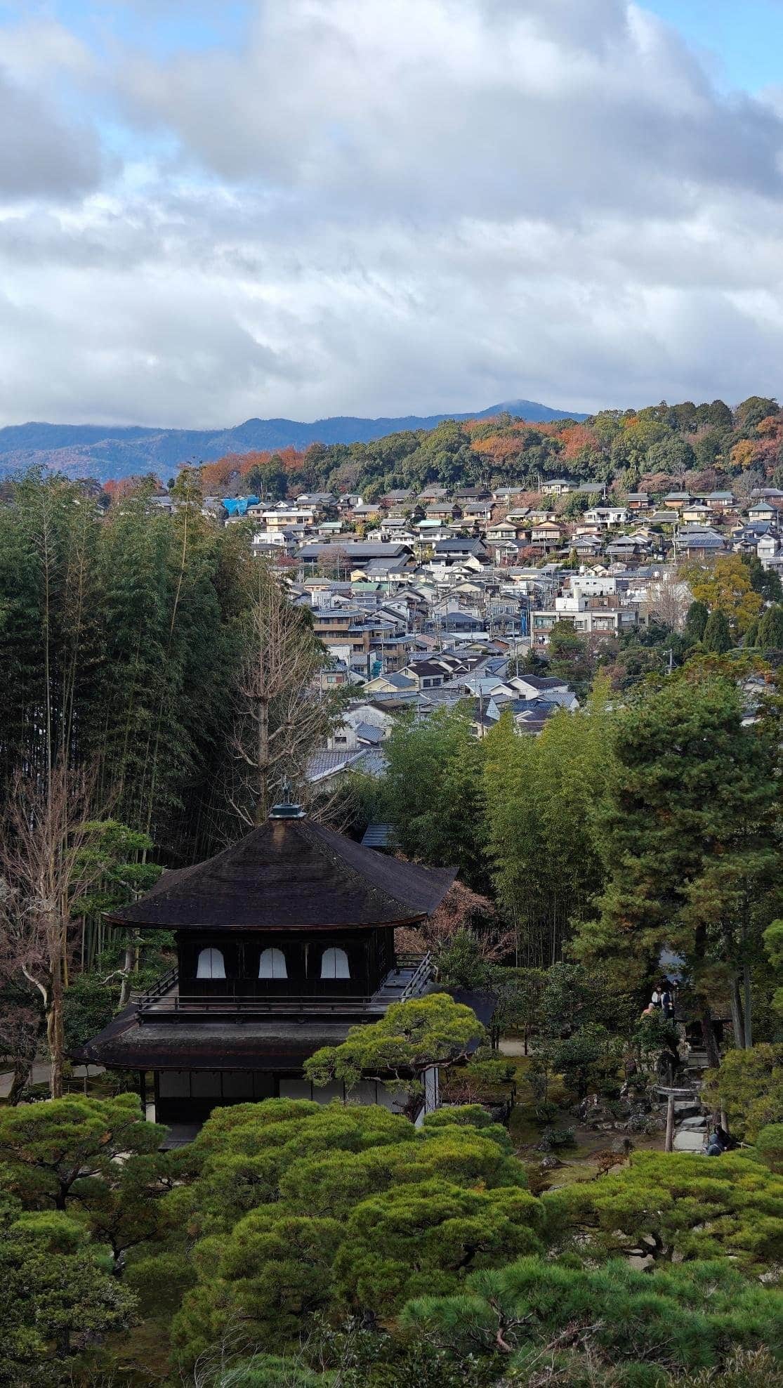 Japanese temple amid lush greenery and mountain backdrop