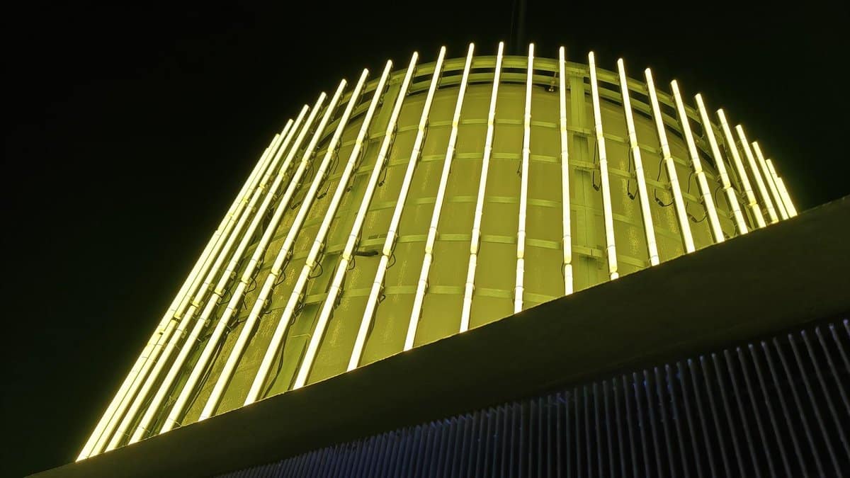 Neon-lit cylindrical structure at night