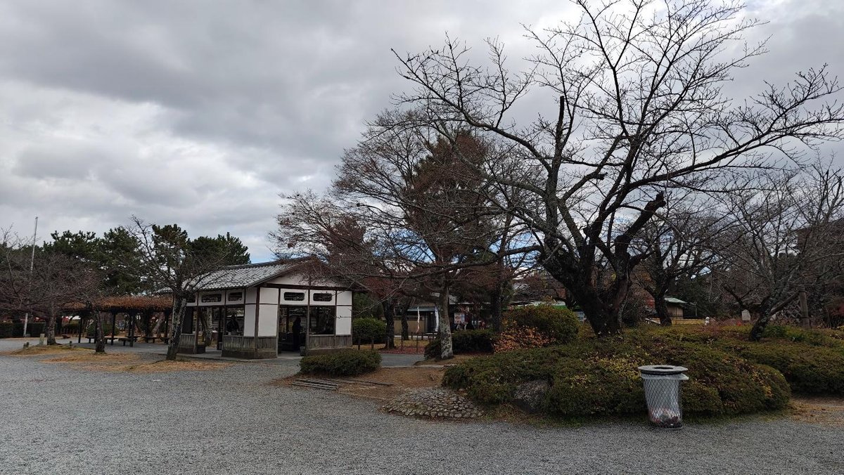 Park with bare trees and small pavilion under cloudy sky