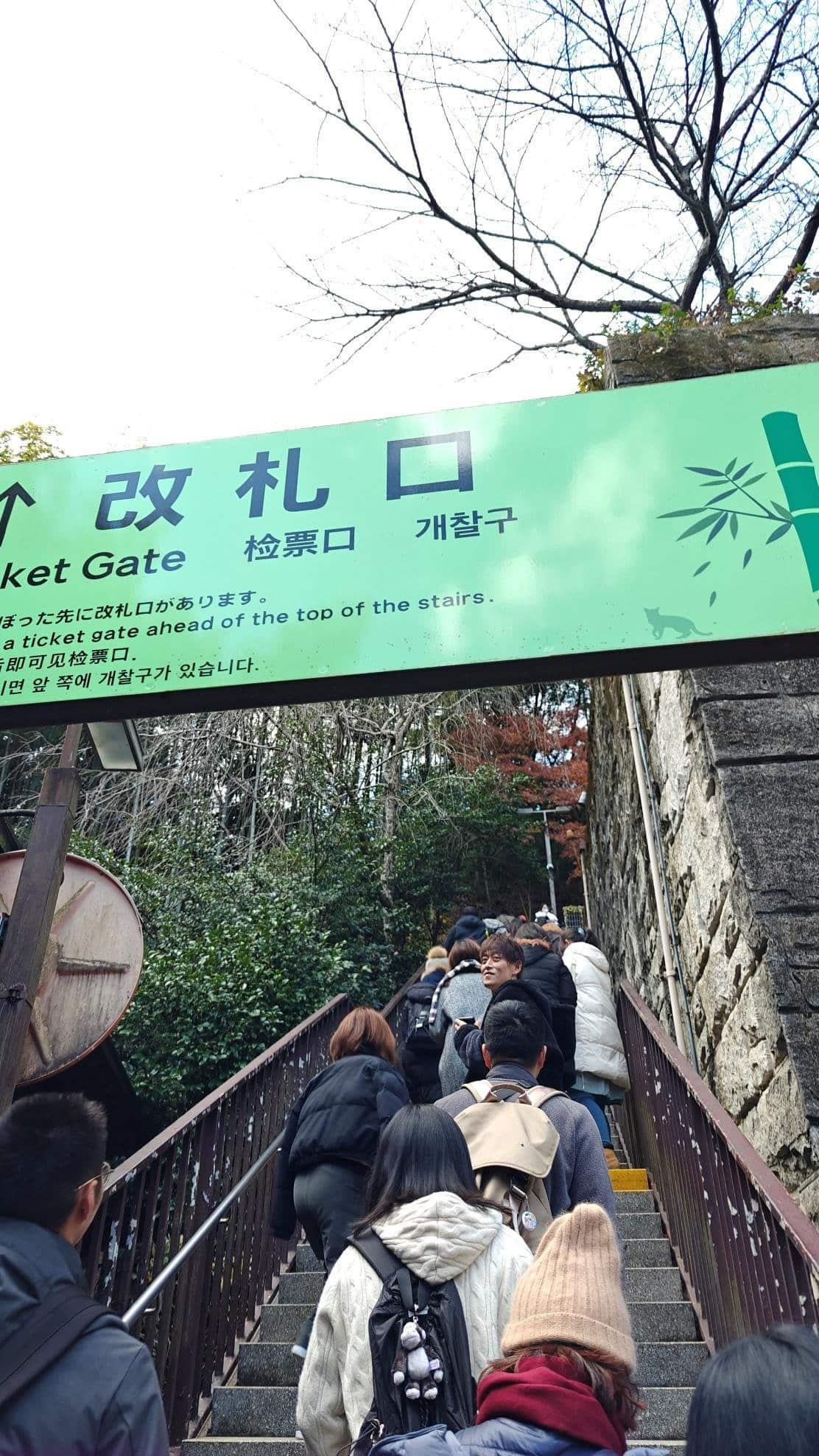 People ascending outdoor stairs under Ticket Gate sign