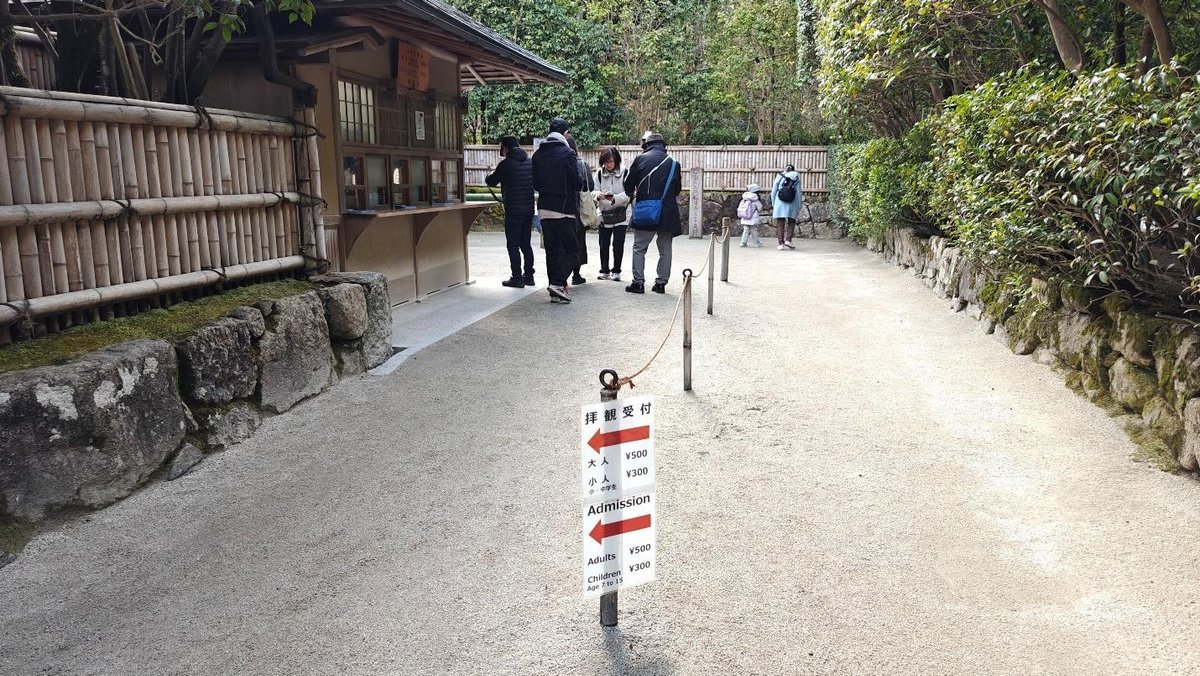 People buying tickets at outdoor booth with bamboo fencing