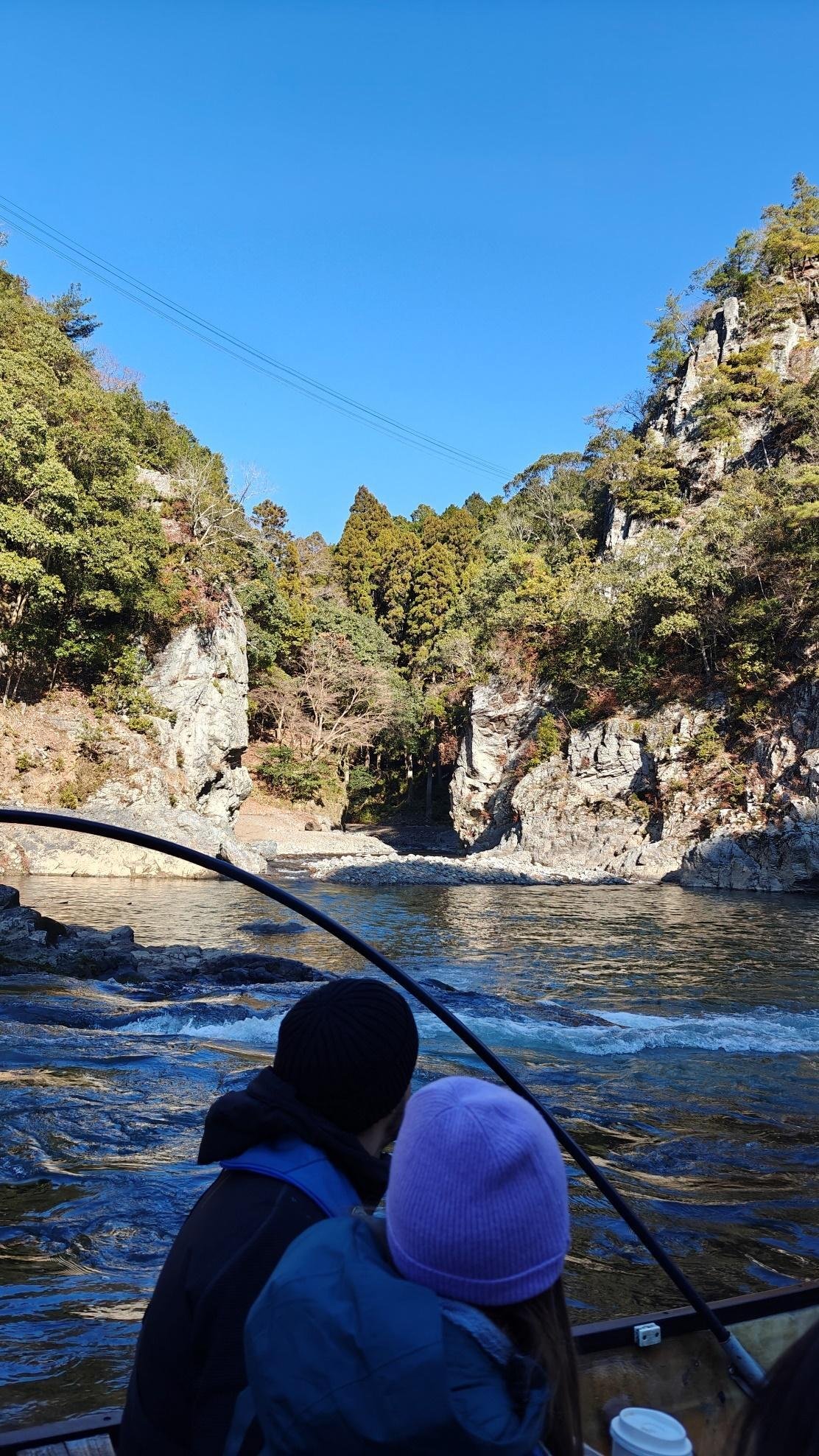 People enjoying a boat ride on a scenic river with rocky cliffs