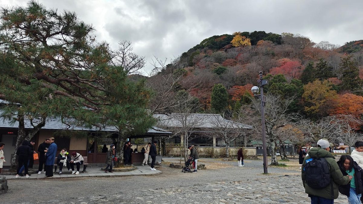 People gather near traditional building amid autumn trees