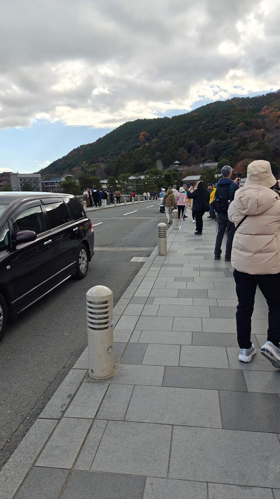 People walking on a scenic mountain path under cloudy skies