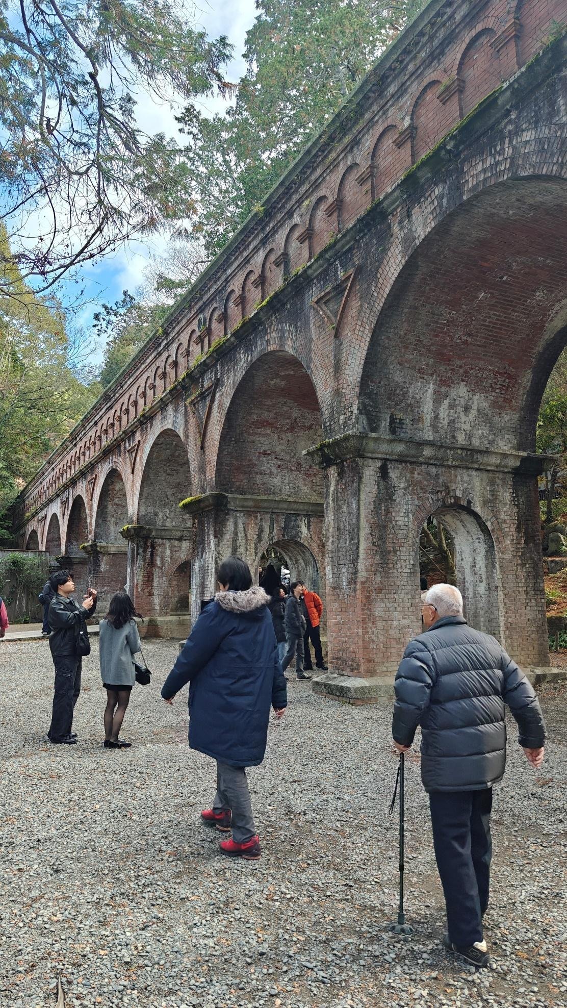 People walking under historic brick aqueduct arches