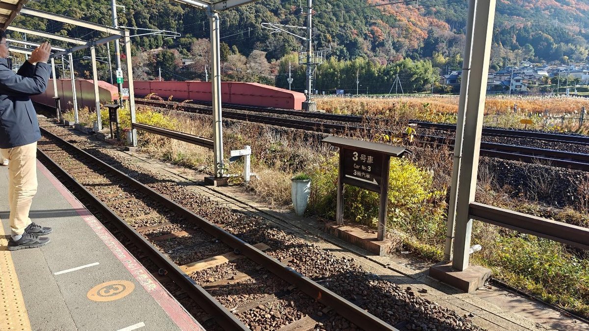 Person photographing train tracks with scenic mountain backdrop