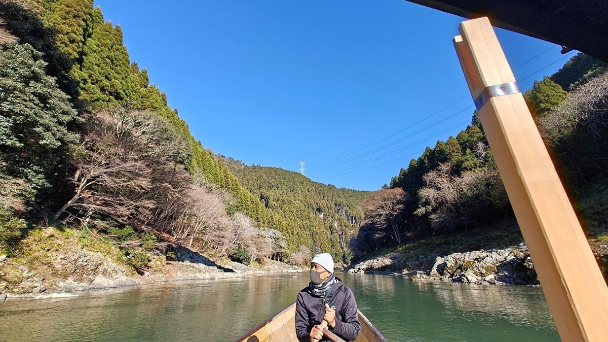 Person rowing boat in a scenic river between forested hills