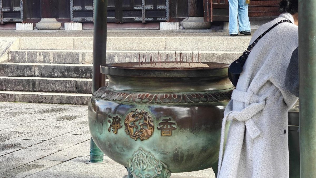 Person standing near large ornate incense burner