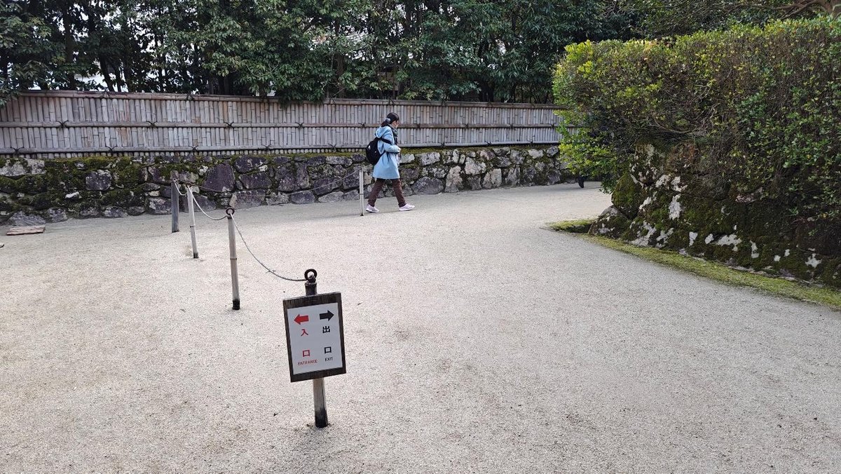 Person walking in stone garden with directional sign