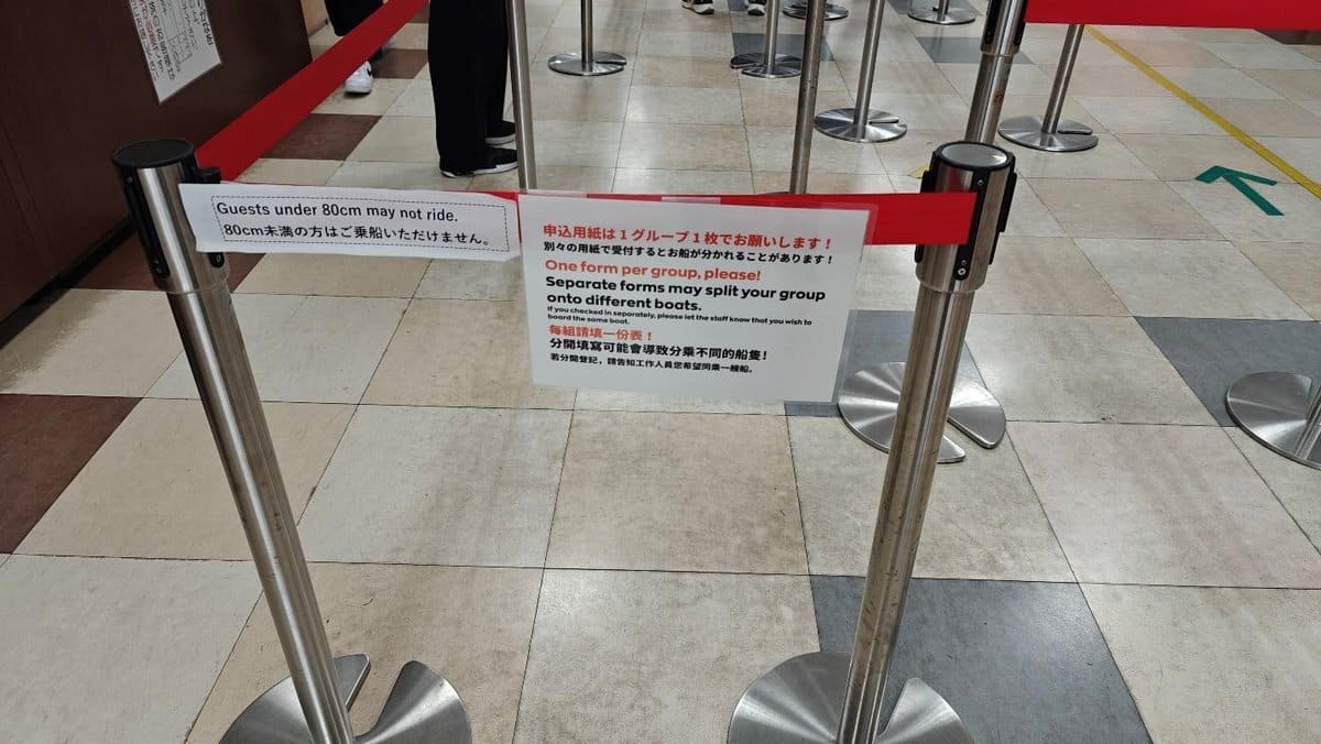Queue barriers with multilingual safety signs in a tiled area