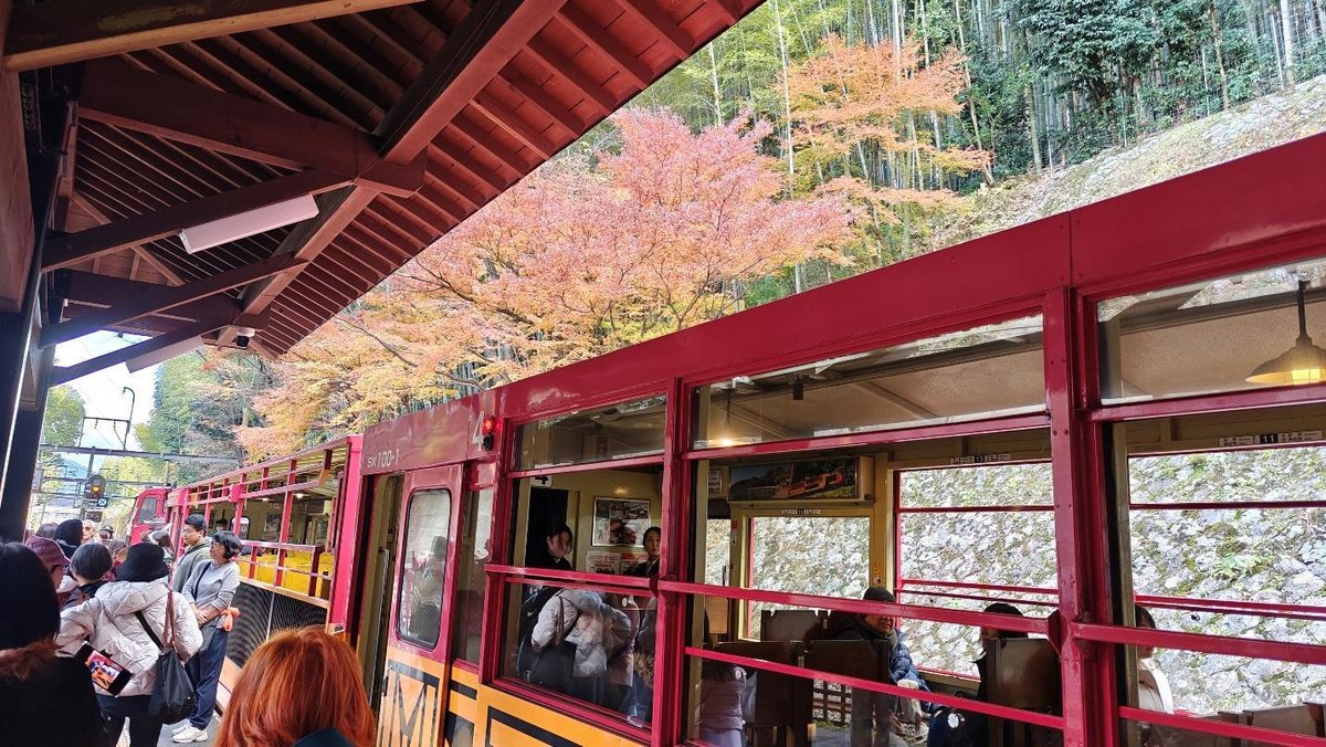Red train at station with vibrant autumn foliage