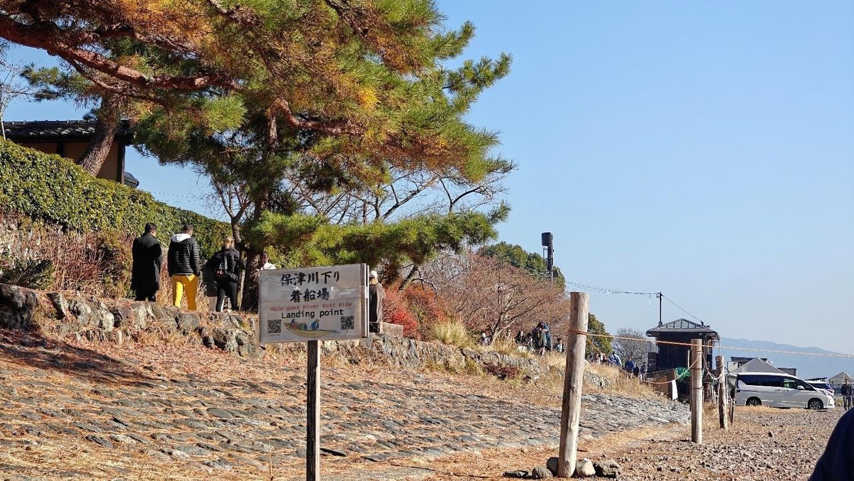 River landing with people walking under autumn trees