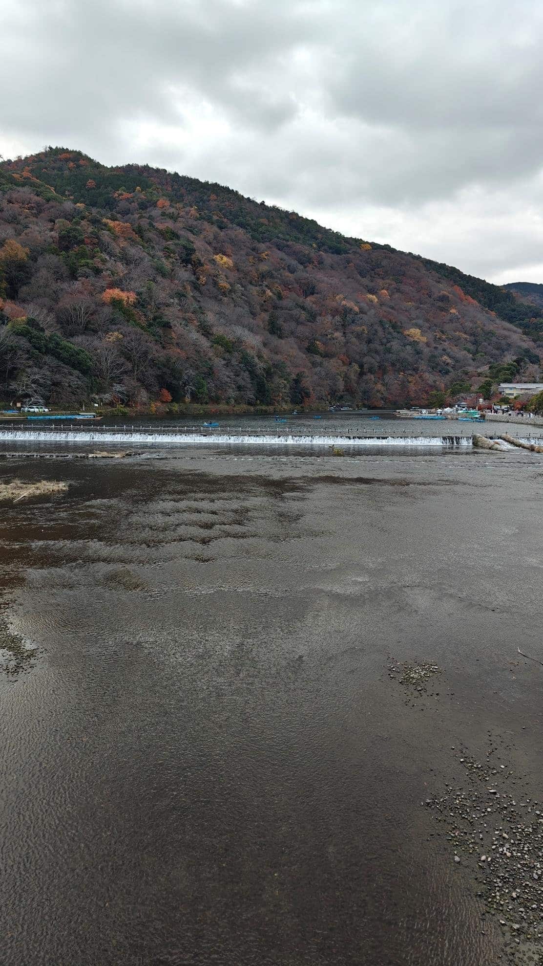 River with autumn trees and hills under cloudy sky
