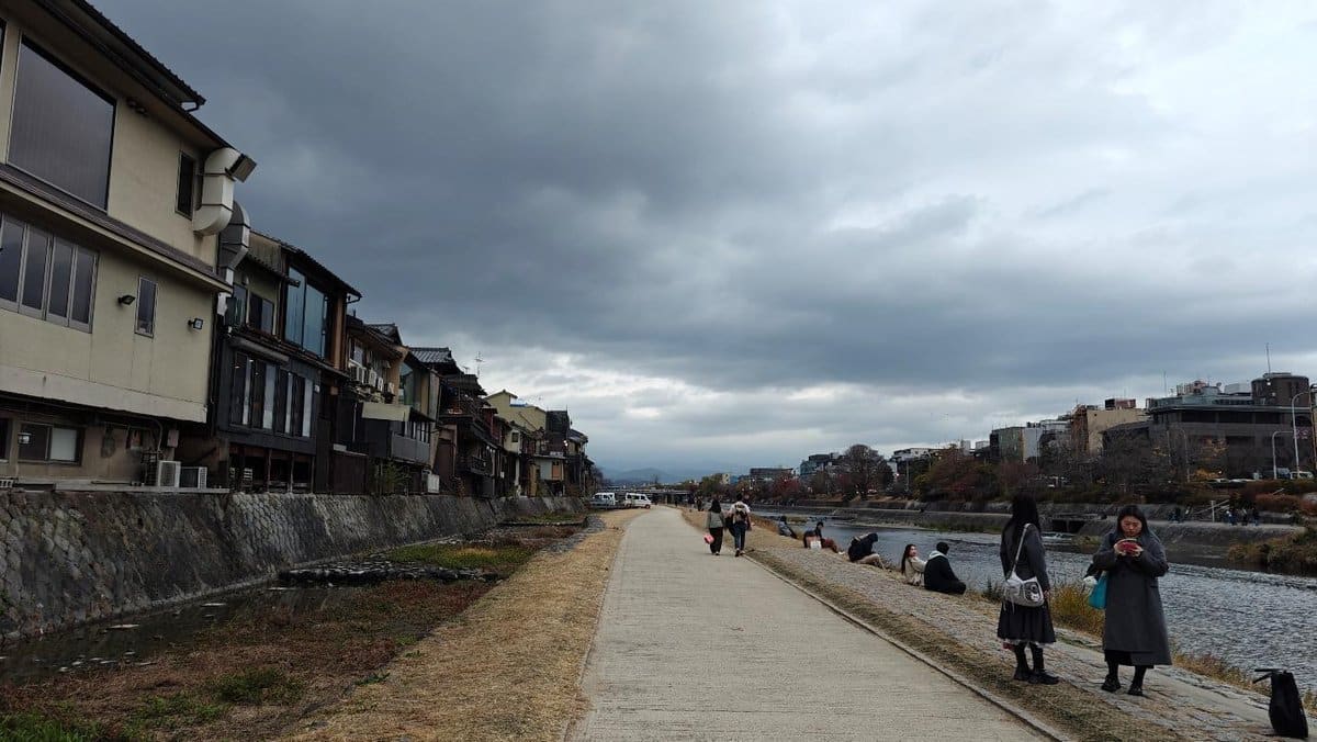 Riverbank promenade with people under overcast skies