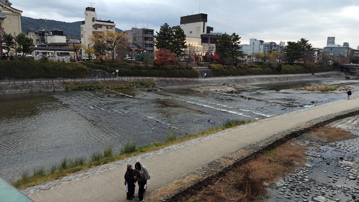 Riverbank view with people on a pathway in urban setting