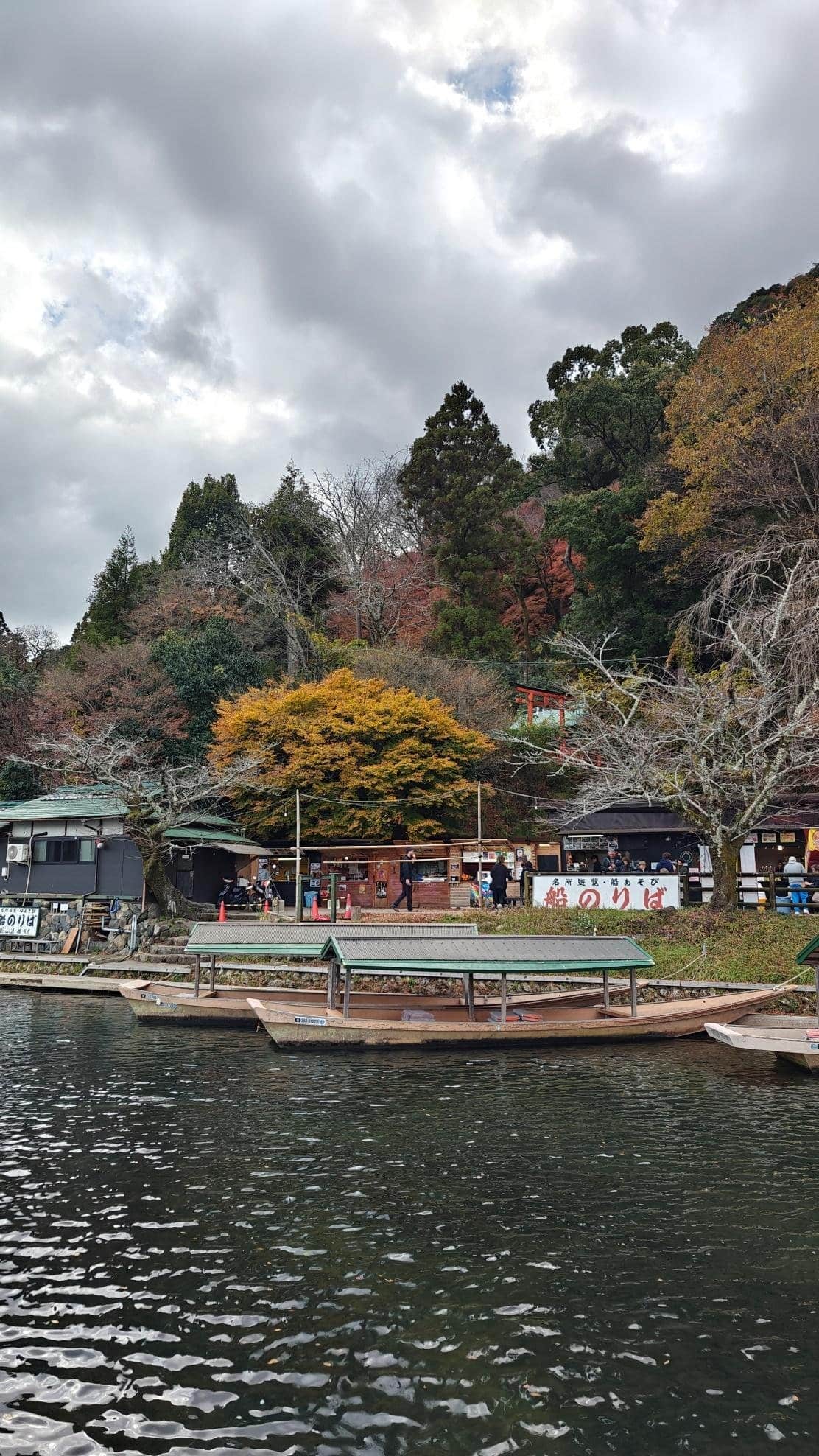 Scenic riverside with boats and colorful autumn trees