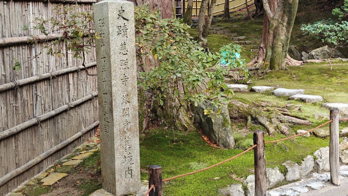 Serene garden with stone marker and bamboo fence