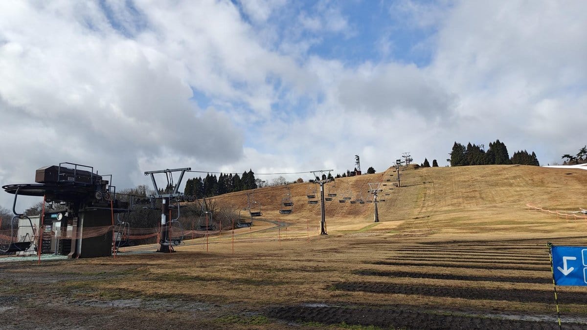 Ski lift on dry grassy slope under clouds