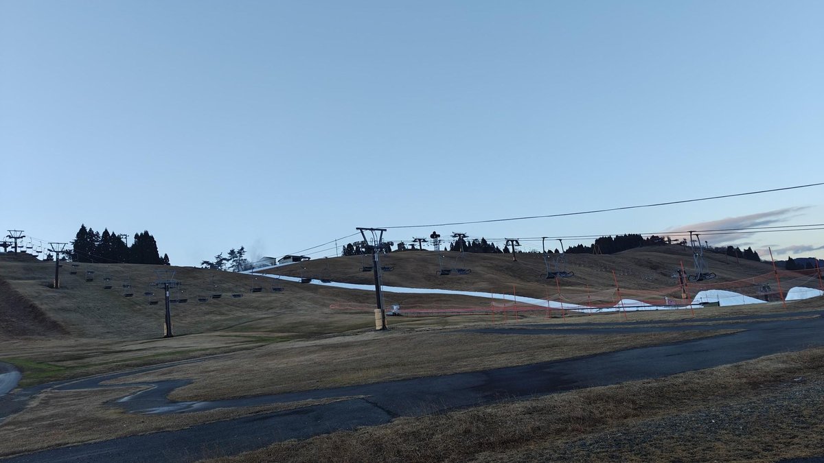 Ski lifts on grassy hill under clear sky