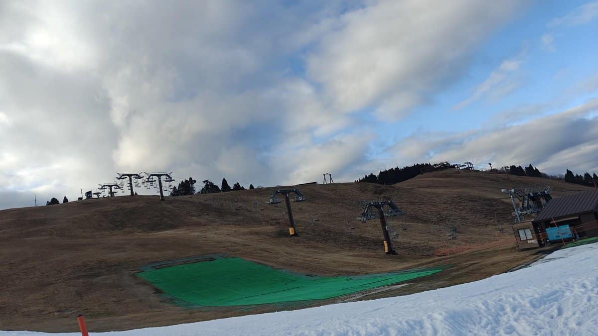 Ski slope with chairlifts under cloudy sky