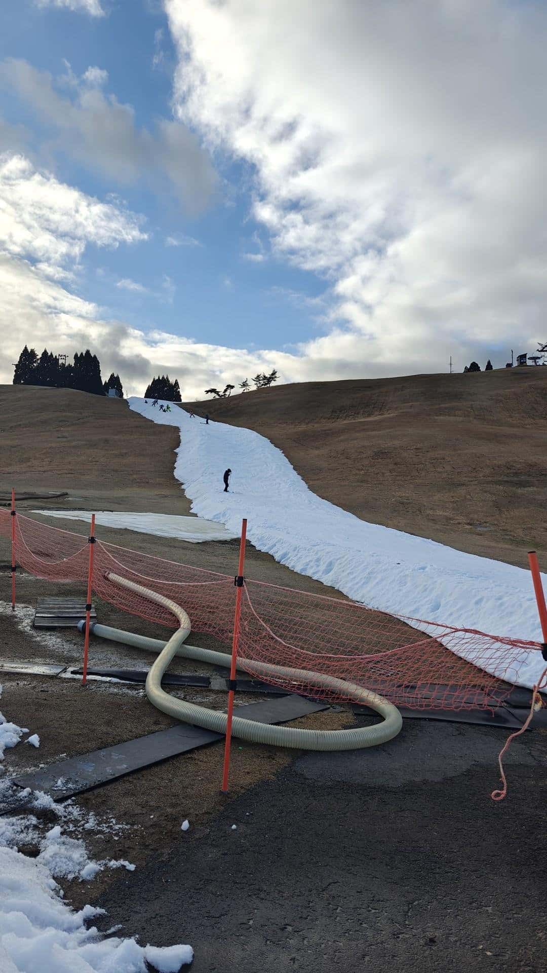 Skiers on snow path under cloudy sky