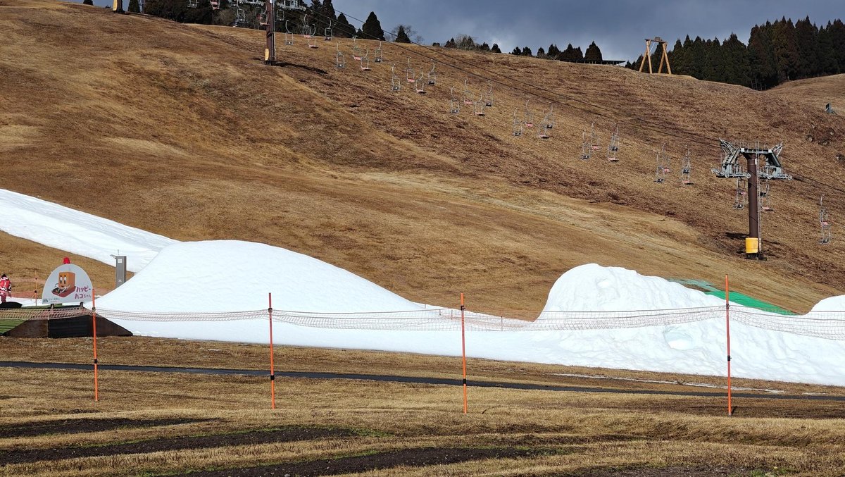 Snow patches on grassy hillside with lift