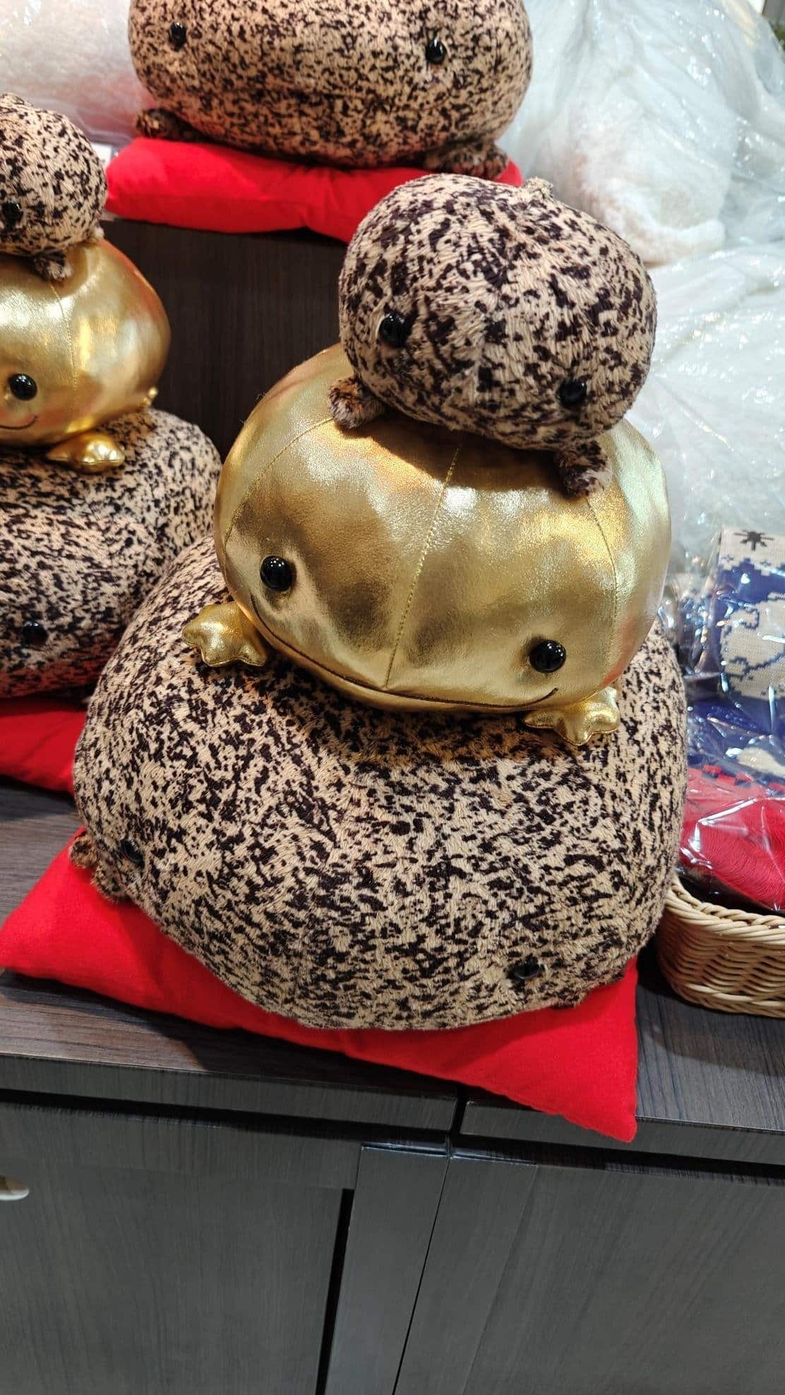 Stacked plush toy frogs with gold details on a shelf