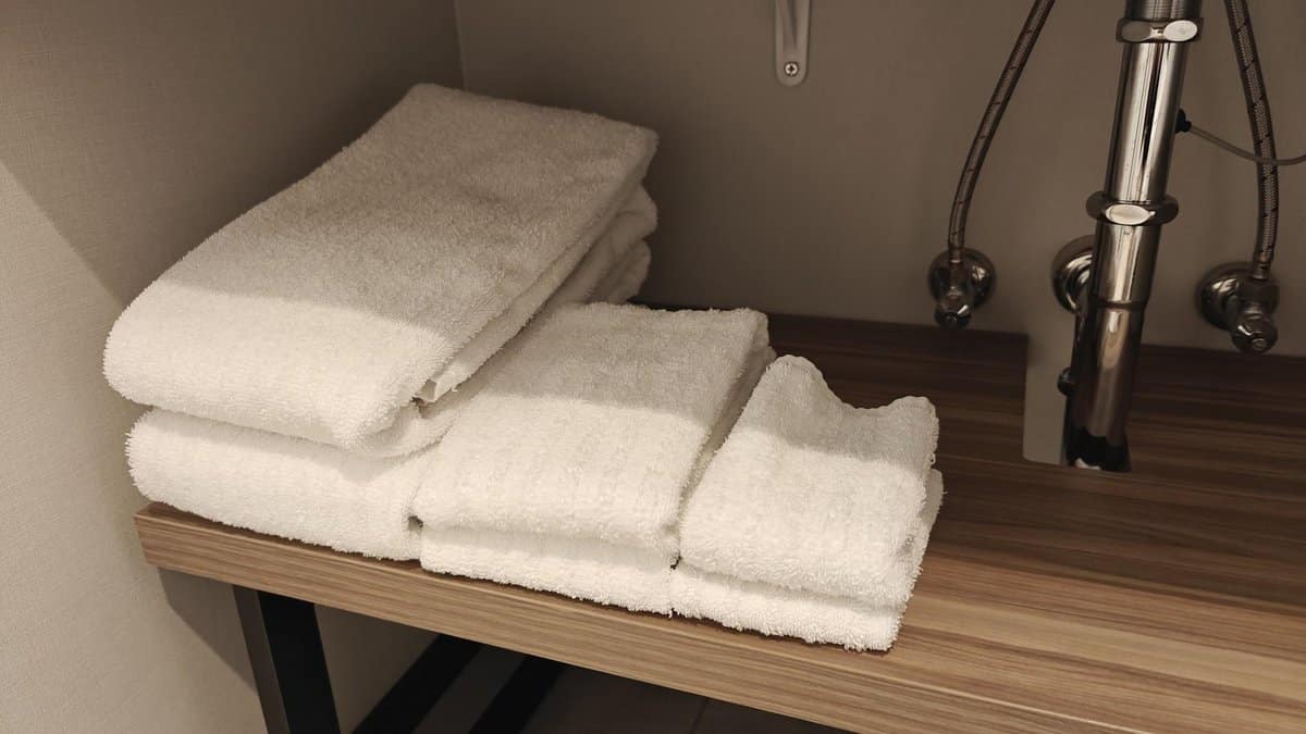Stacked white towels on wooden shelf
