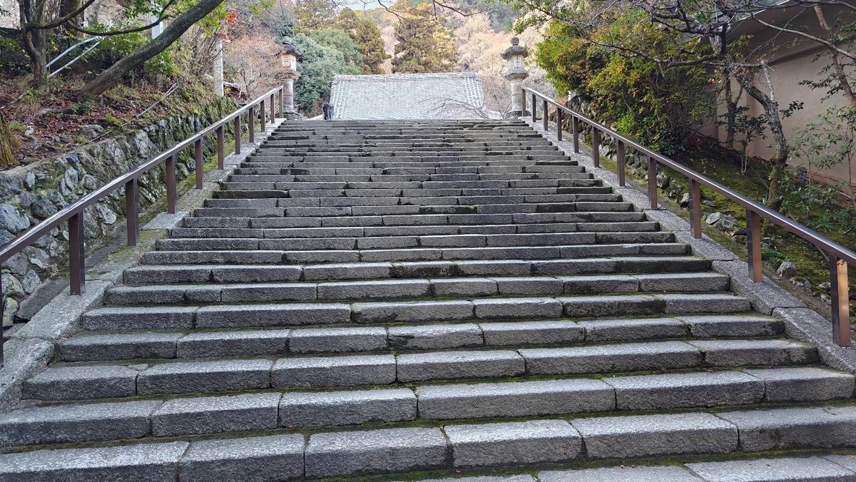 Stone stairs flanked by greenery leading to traditional gate