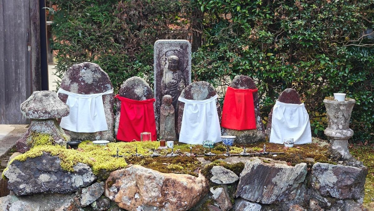 Stone statues with colorful cloths in a Japanese garden setting