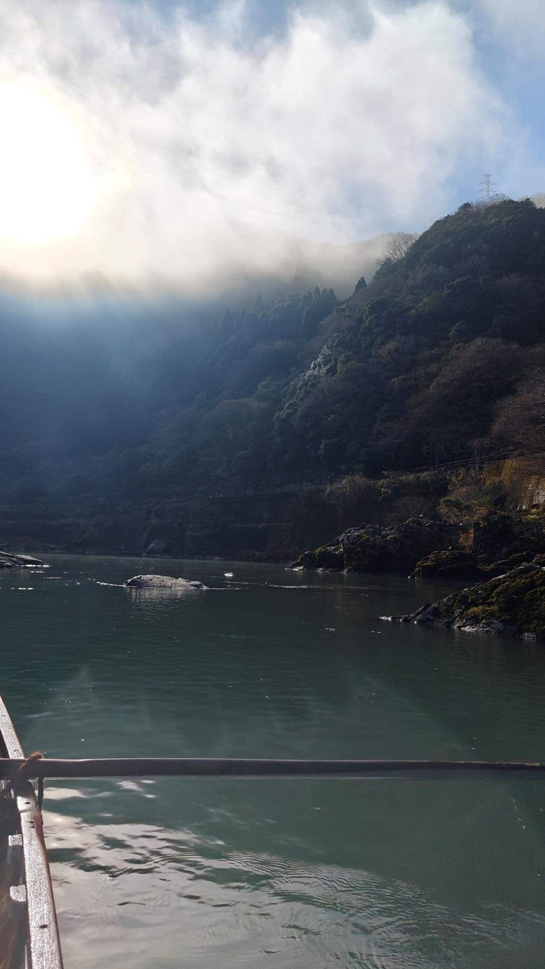 Sunlit mist over a serene lake with forested hills