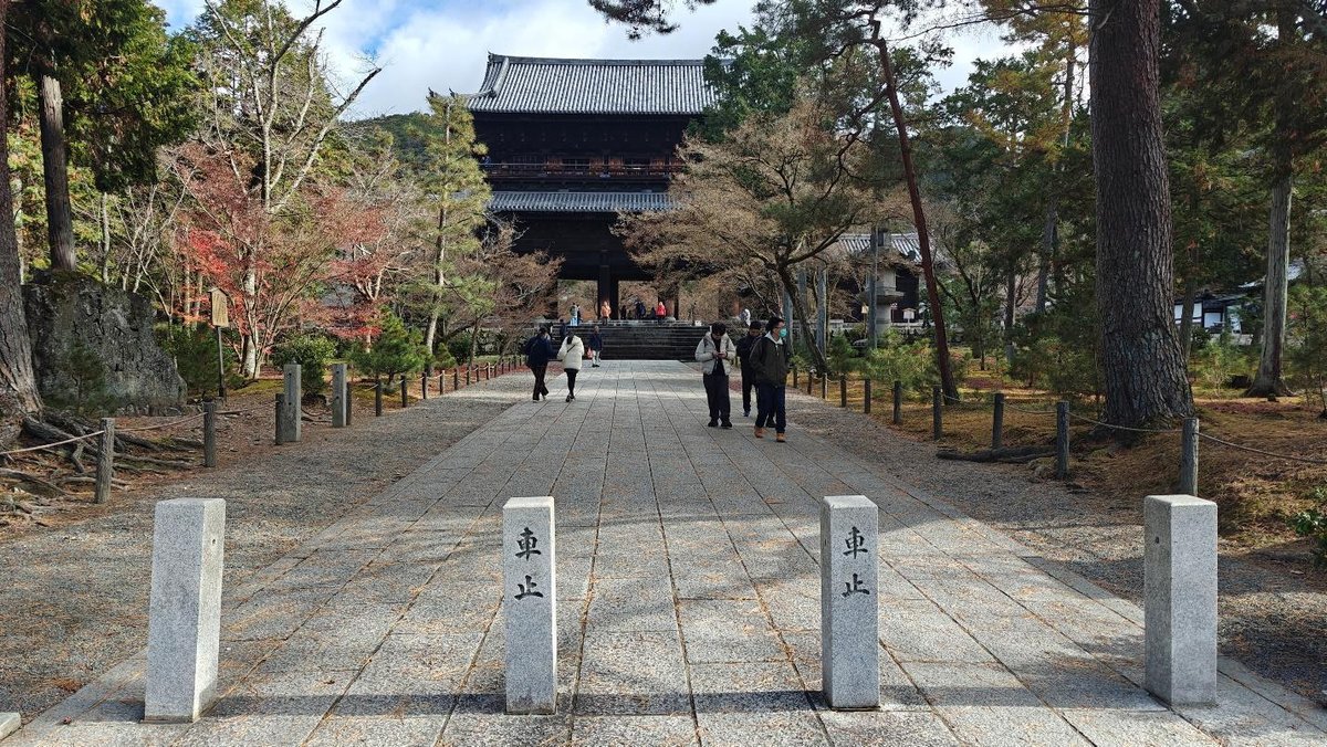 Temple entrance amidst trees and walking visitors