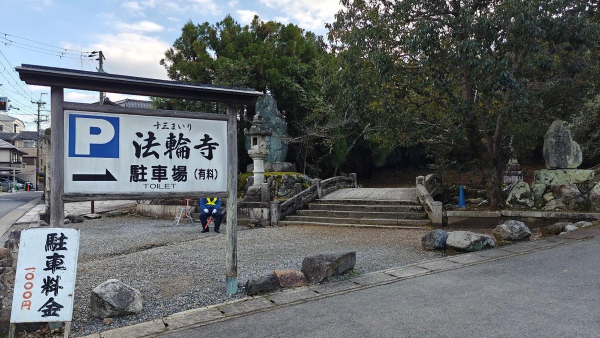 Temple entrance with parking sign and stone lantern