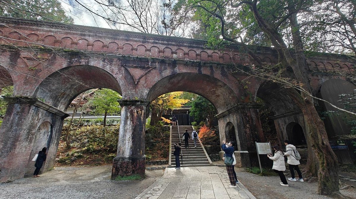 Tourists exploring historic brick aqueduct in natural setting