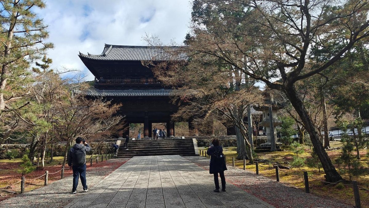 Traditional Japanese gate surrounded by trees and tourists