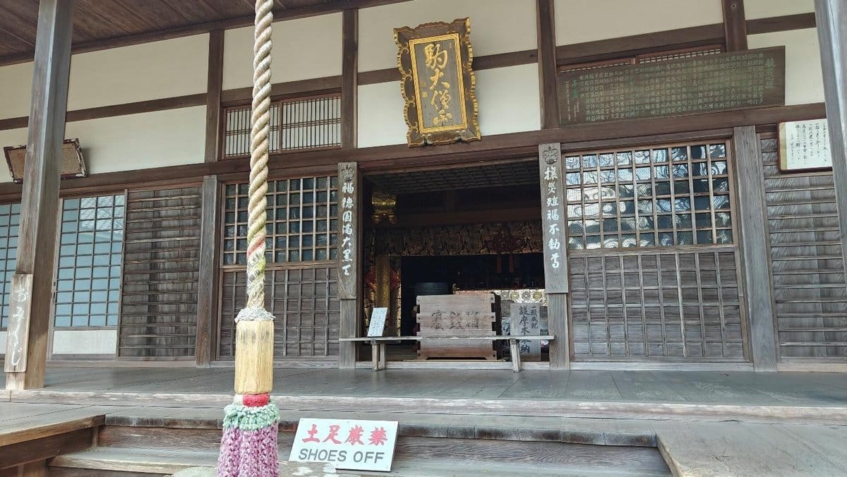 Traditional wooden temple entrance with 'shoes off' sign