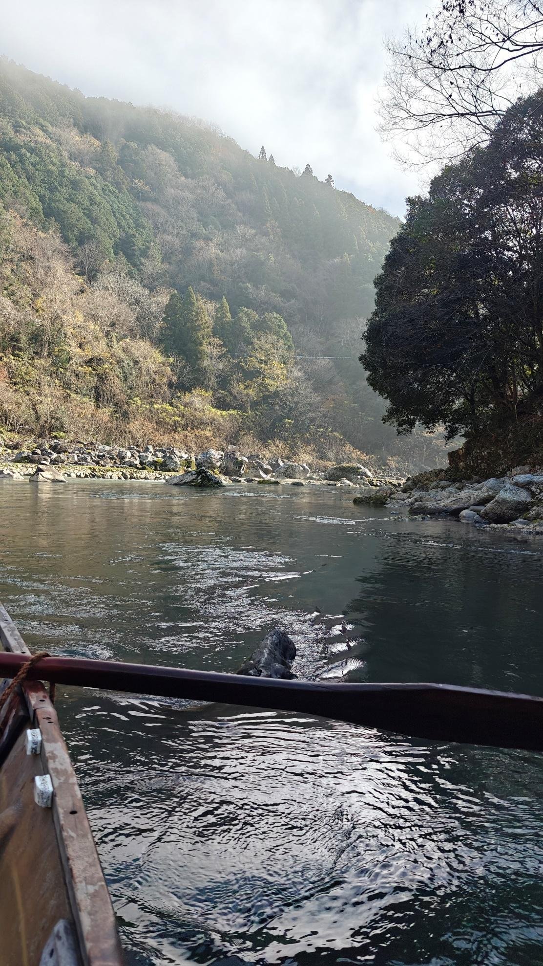 Tranquil river scene with tree-lined hills under cloudy sky