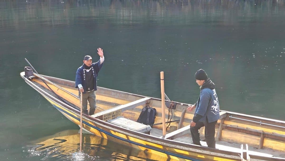 Two men on a wooden boat in calm water