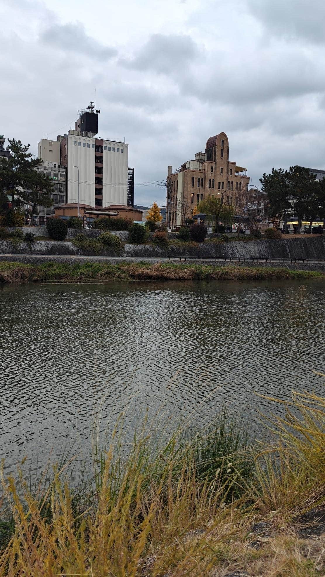 Urban river view with modern and historic buildings, cloudy sky