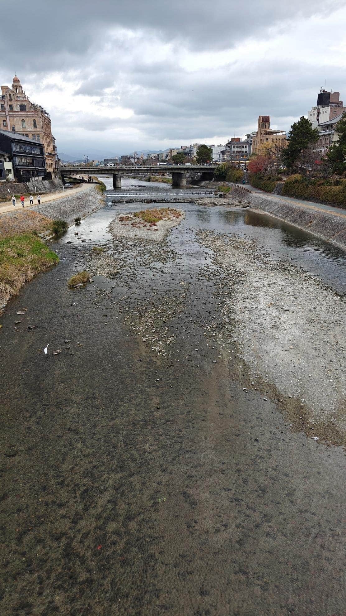 Urban river with bridges under cloudy sky