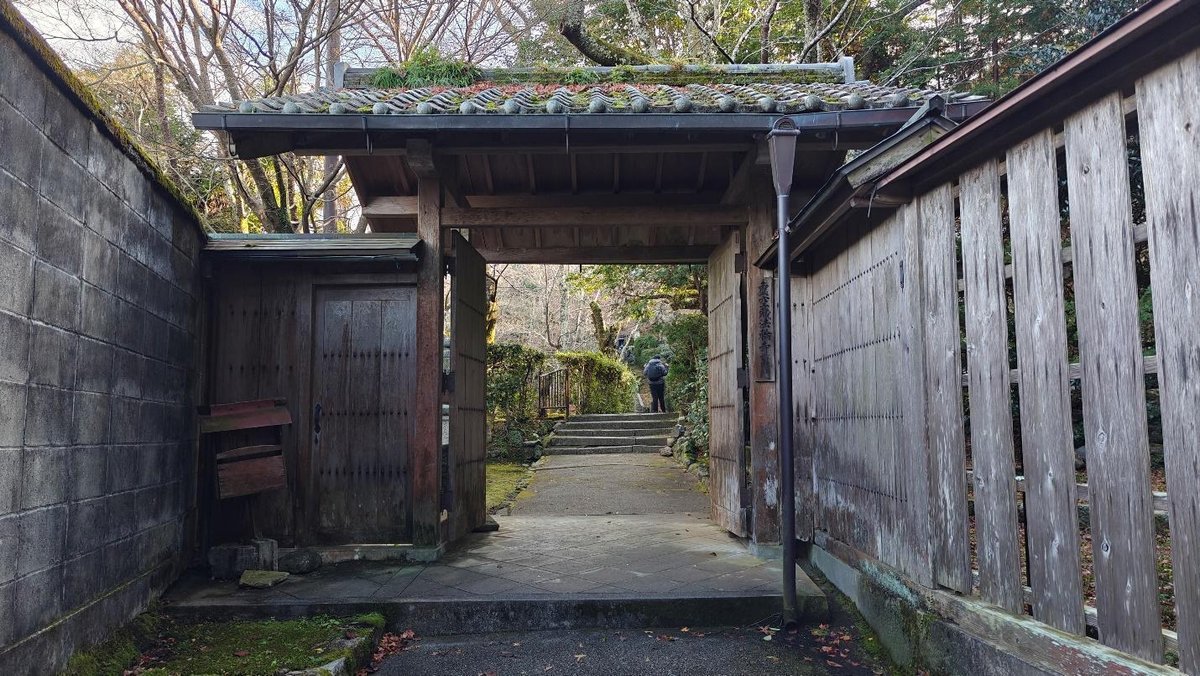 Wooden gate leading to garden path with person in distance