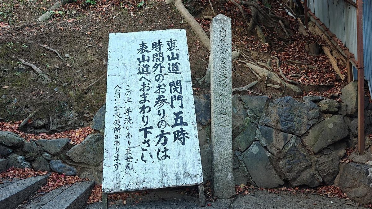 Wooden sign with Japanese text by rocky path