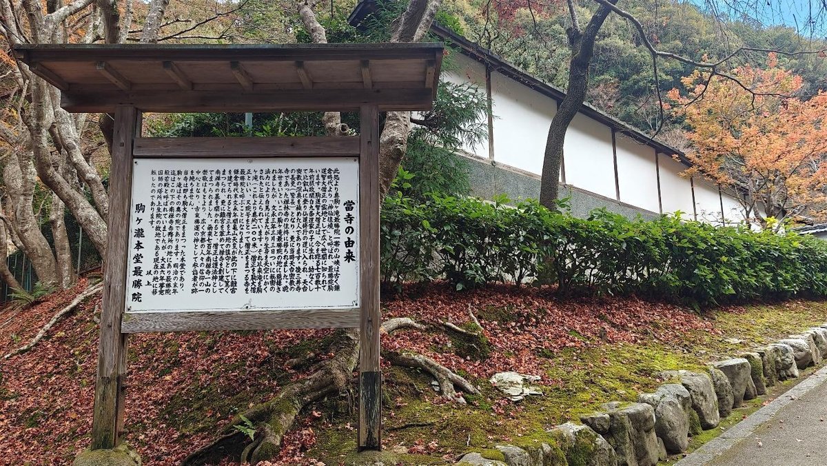 Wooden sign with Japanese text in autumn garden setting