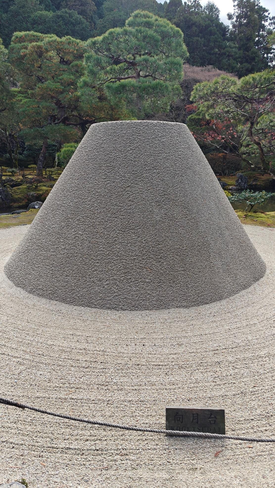 Zen garden with sand cone and lush pine trees