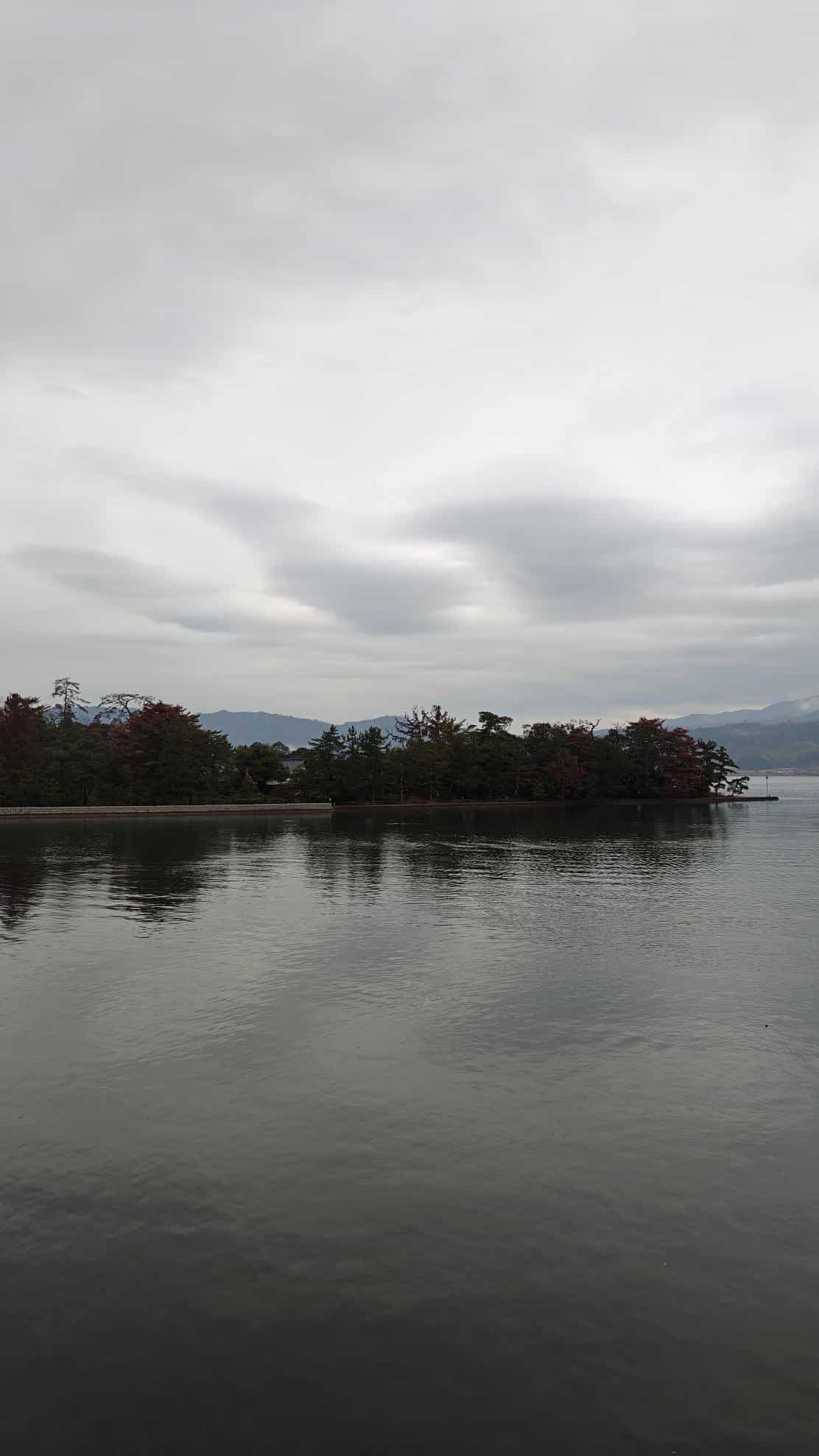 Calm lake with a cloudy sky and distant island