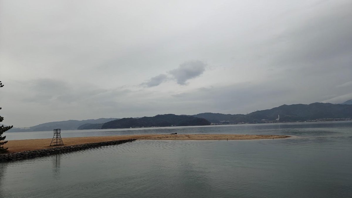 Calm waters with distant hills under cloudy sky